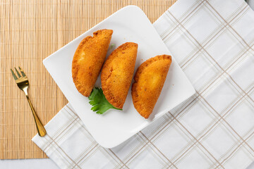 Golden crispy fried empanadas serving on white plate