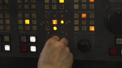 Technician operating industrial control panel with multiple buttons and lights. Stock clip
