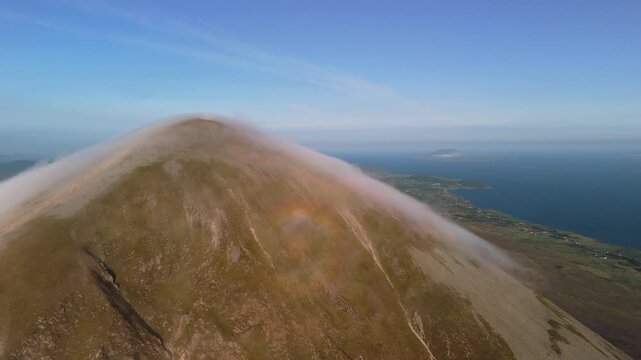 Amazing 4K aerial video of flying above and around Most Famous mountain in Ireland - Croagh Patrick in windy weather, with moving fog and clouds with breathtaking views around, Westport, Ireland