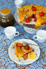 Piece of strawberry pie with lemon and fresh berries on lace light blue tablecloth