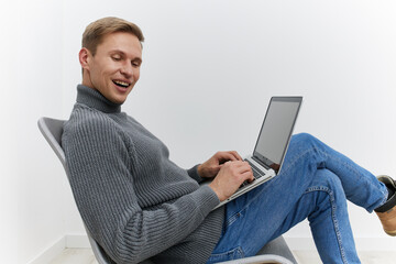 smiling man working on laptop wearing gray sweater blue jeans sitting modern chair isolated on white background casual digital nomad concept
