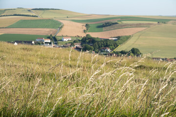 Fototapeta premium Cap Blanc-Nez, Escalles, Pas-de-Calais, Hauts-de-France, France, July 29th, 2025, Experience a breathtaking view of the lush, rolling hills and a quaint village beautifully set under clear blue skies