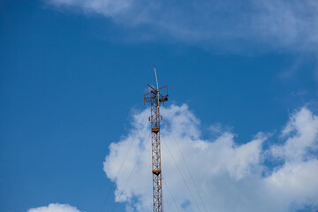 Obraz premium High steel tower with mobile phone antenna and radio equipment against a blue sky for wireless cellular communication network