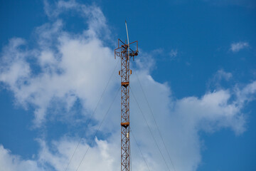 Obraz premium High steel tower with mobile phone antenna and radio equipment against a blue sky for wireless cellular communication network