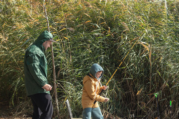 Little boy and his father fishing on river