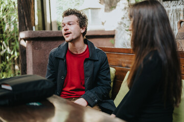 A man and woman having a discussion while seated at a wooden table, depicting interaction and...