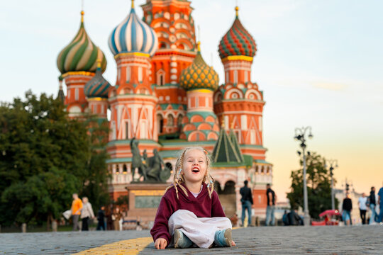 Cute little child girl traveling with family on Red Square with a view to St. Basil's Cathedral in Moscow.