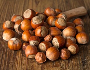 A pile of ripe hazelnuts resting on a rustic wooden surface with a spoon
