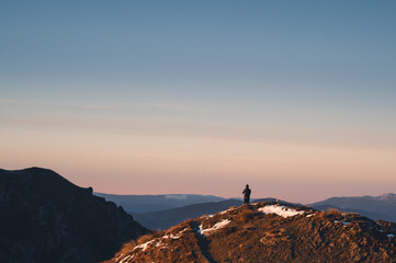 Hiker Watching Sunrise Over Lake Wanaka from Roys Peak Summit, New Zealand