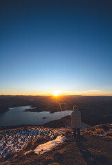 Hiker Watching Sunrise Over Lake Wanaka from Roys Peak Summit, New Zealand