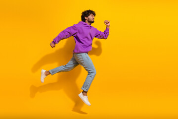Confident young man in a purple hoodie and jeans posing dynamically against a bright yellow background