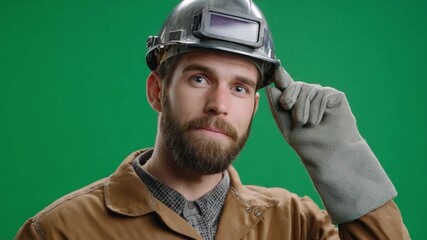 Thoughtful Artisan: A skilled artisan, clad in workwear, thoughtfully adjusts his protective headgear against a verdant backdrop, a portrait of dedication and expertise.