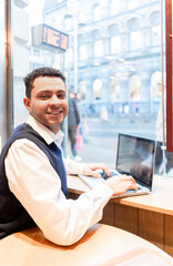 Fototapeta premium A young elegant executive of mixed ethnicity smiles at the camera, holding a laptop in historic Dublin.