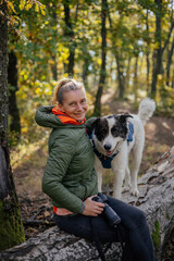 Photographer and hiker woman enjoying walking her dog off-leash in an autumn forest. 
