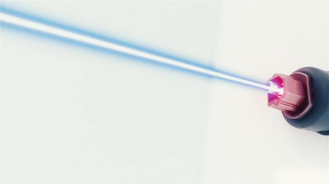 Un connettore emette un fascio di luce laser rossa che vira al blu in uno spazio bianco