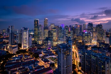 Naklejka premium A travel landscape of city buildings glowing with light at dusk.