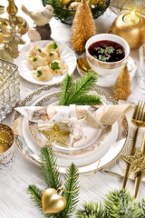 Christmas table setting with decors in white and gold colors and traditional dishes