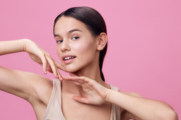 Young female model with a joyful expression on a pink background, showcasing beauty and confidence...