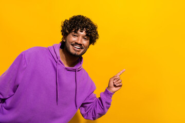 Cheerful man in purple hoodie posing against a vibrant yellow background with a joyful expression...
