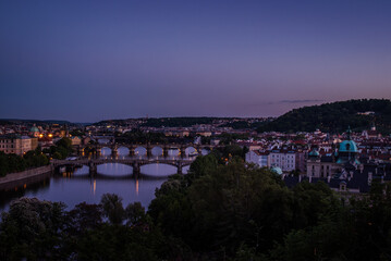 Twilight view of bridges over the Vltava River in Prague, Czech Republic, with bluish evening tones and reflections of street lights on the water