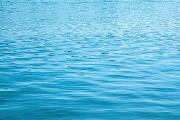 Calm river surface displaying gentle ripples and seamless blue hues under soft sunlight
