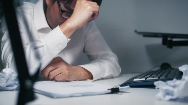 Close-up of Asian Businessman Manager Hand Crumpling Paper ball. Upset, Anxious Asian Businessman making mistake, Feels Burnout, Failure Crumpling business paper and Throw away sit at desk in office.
