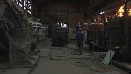 Fototapeta premium Foundry workers casting molten metal into a mold. Stock clip