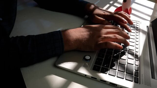 Hands Typing on Laptop Keyboard, Hands typing on a laptop keyboard in a dimly lit room