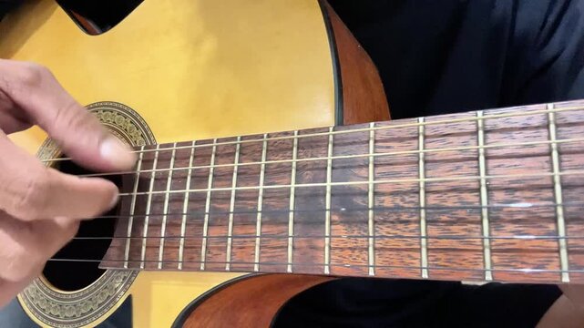 pluck the guitar strings slowly with a relaxed rhythm