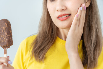 Asian woman feel sensitive teeth after eating ice cream, female suffer tooth, decay problems,...