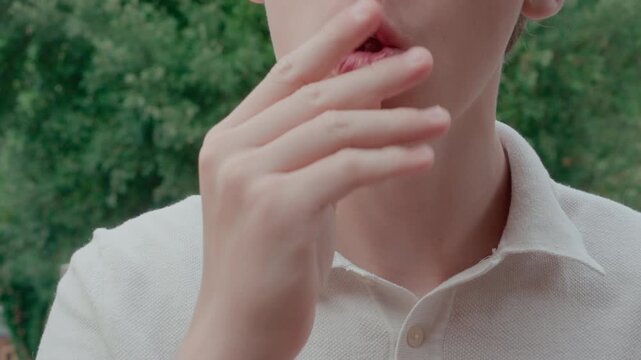 Teenage boy moves upper and lower clear dental aligners with his hands to show their structure and occlusion outdoors