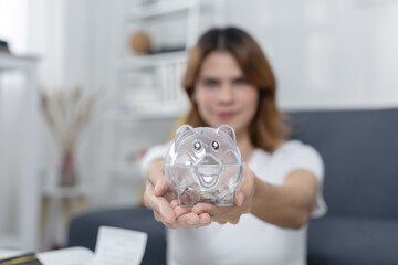 women holding transparent piggy bank filled with coins, showing concept of saving money, personal...