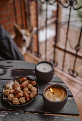 Burning handmade candle and nuts on rustic wooden table with blurred background and dog