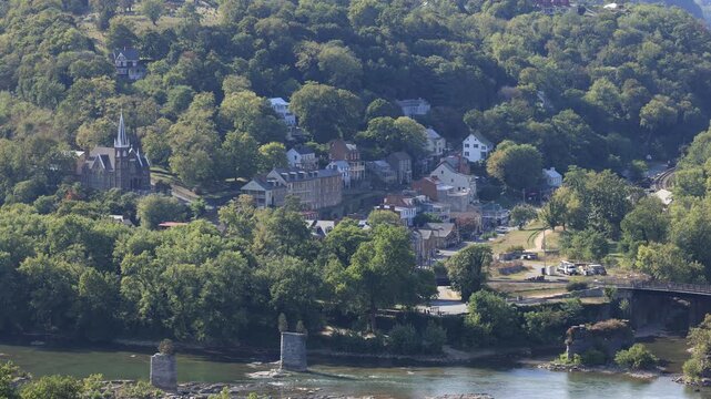 High angle view of historic Harpers Ferry where the Potomac and Shenandoah Rivers meet. The town&rsquo;s old bridge ruins and church spires highlight its scenic and historic charm on a late summer day.