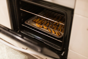 Baked potato wedges golden brown on parchment paper coming out of the oven