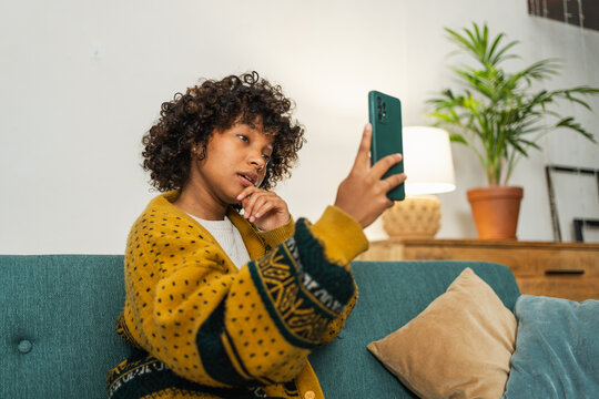 African American girl holding smartphone having video chat. Female blogger chatting with best friends in social network. Young woman having virtual meeting online chat video call at home - Powered by Adobe