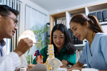 A doctor and a nurse are examining a model of a heart. The doctor is explaining the anatomy of the heart to the nurse
