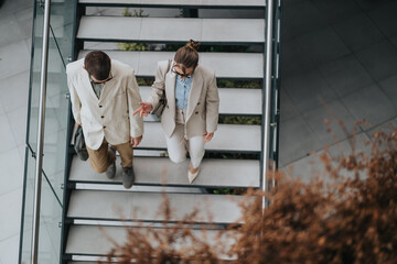 Two business professionals discussing work while descending modern office stairs.