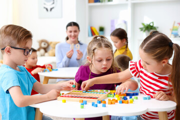 Naklejka premium Cute children and teacher at white tables during lesson in elementary school
