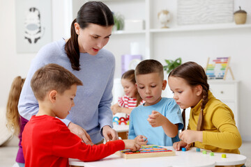 Obraz premium Cute children and teacher at white table during lesson in elementary school