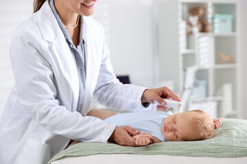 Pediatrician examining little child with infrared thermometer in hospital, closeup. Checking baby's...