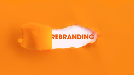 The Strategic Word REBRANDING Revealed Through a Horizontal Tear in a Bold Orange Paper Background, Representing Change, Strategy, and New Direction.