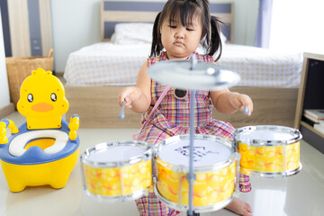 A cute little girl is having fun playing a toy drum set,Happy white girl, drummer, girl playing...