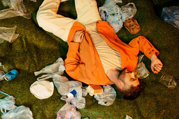 Young man lies in plastic waste highlighting environmental challenges today