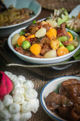 Top-view still life of authentic Nam Prik Long Ruea, a traditional Thai chili paste dip, presented in ceramic bowls on a wooden board and banana leaf. The composition includes fresh seasonal vegetable
