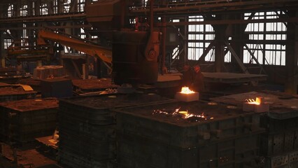 Foundry workers pouring molten metal into molds in industrial plant. Stock clip