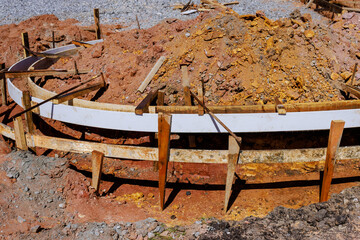 Wooden forms for concrete are set for sidewalk curb in construction site, surrounded by dirt gravel