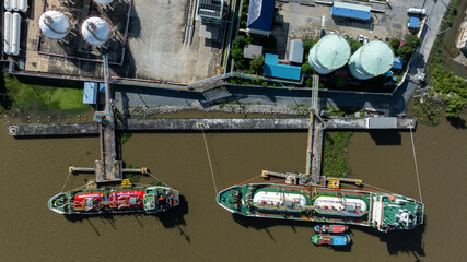 Fototapeta premium Aerial top view white gas storage tank with LPG tanker ship, LPG distribution station facility, Gas LPG manufacturing industry, Liquefied natural gas storage tank industrial gas.