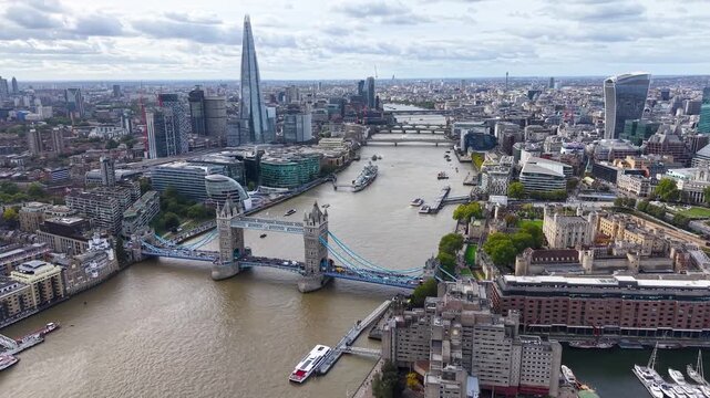 Cinematic aerial view of Tower Bridge (London Bridge) and the historic Tower of London with the stunning City of London skyline and its iconic modern architecture.