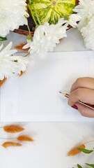 Creative Workspace with Hand Holding Pencil and White Chrysanthemums
